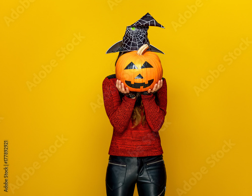 woman holding sad jack-o-lantern pumpkin in front of face