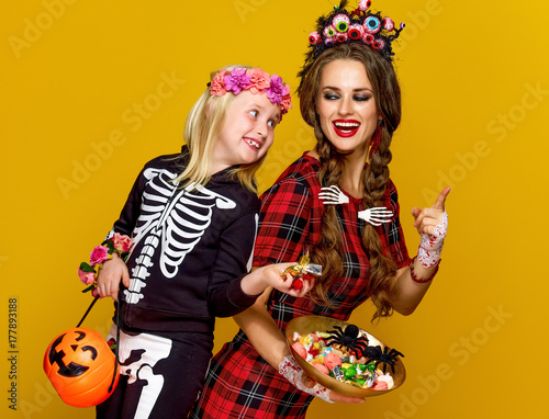 mother and child stealing halloween candies isolated on yellow