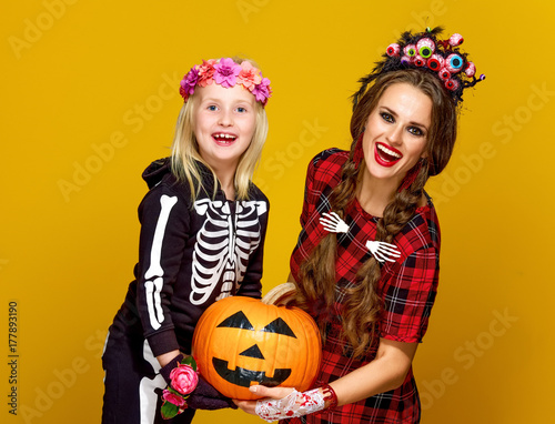 happy modern mother and child holding jack-o-lantern pumpkin