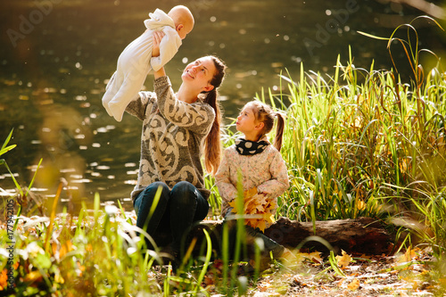 Happy family concept. Mother and children having fun in the autumn forest next to a lake. Motherhood concept
