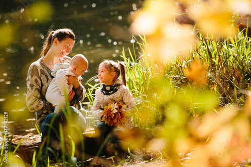 Happy family concept. Mother and children having fun in the autumn forest next to a lake. Motherhood concept