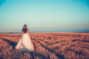 Beautiful landscape with a bride running on empty field, concept , corporate photo , Bride in wedding dress goes on the road in a field at sunset