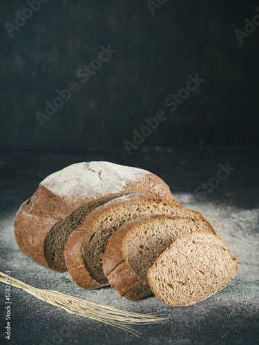 Fotoobraz na płótnie Pokrojony domowej roboty sourdough żyta chleb z żyto mąką na czarnym textured tle. Skopiuj miejsce. Niski klucz