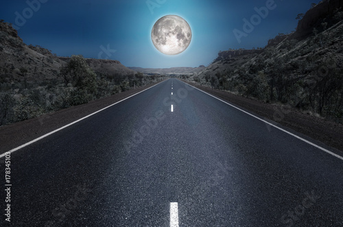 Full moon over the empty highway through the australian outback. Element of this image furnished by NASA