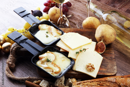 Delicious traditional Swiss melted raclette cheese on diced boiled or baked potato served in individual skillets