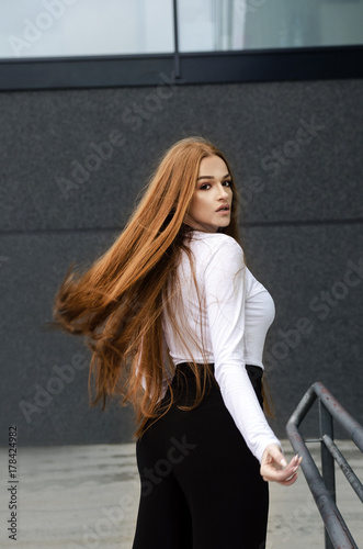Plakat Młoda piękna atrakcyjna kobieta z długim czerwonym włosianym trwanie outside. Portret mody i urody.
