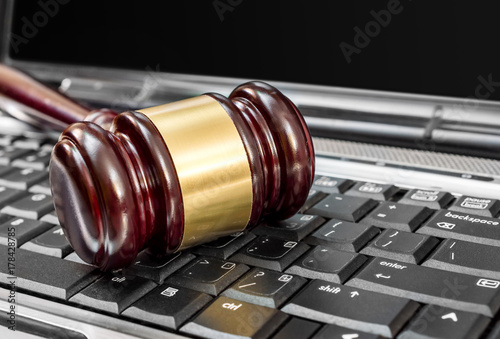 Judge's wooden gavel on laptop keyboard. Close up. Online auction and law concept.