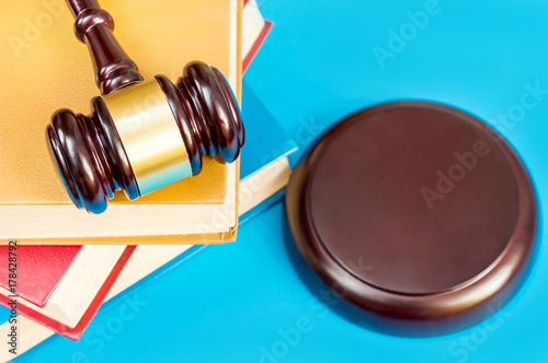 Judge's wooden gavel and stack of books on blue background.