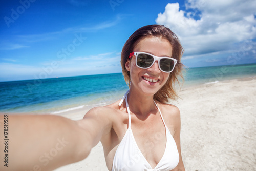 Beautiful young woman doing selfie on the beach, tropical paradise