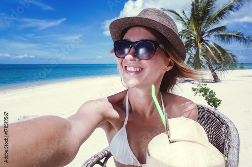 Beautiful young woman doing selfie on the beach, tropical paradise
