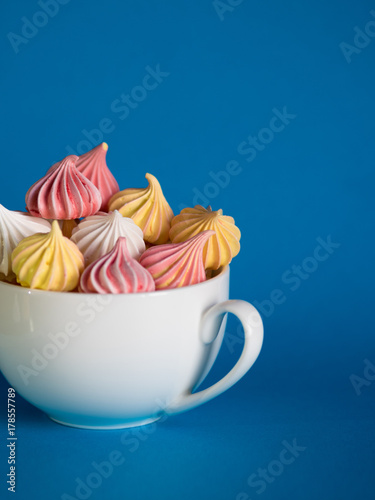 Dessert with meringue, a lot of colorful meringues in the tea Cup