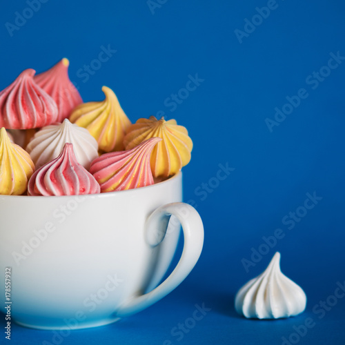 Dessert with meringue, a lot of colorful meringues in the tea Cup