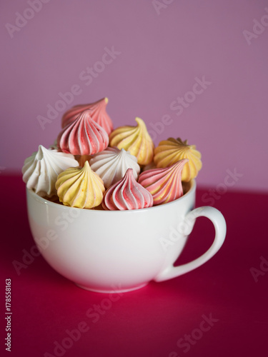 Dessert with meringue in the tea Cup. Bright pink background