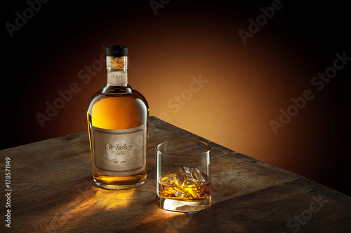 view of glass of  whiskey and a bottle aside on color background. self made label.