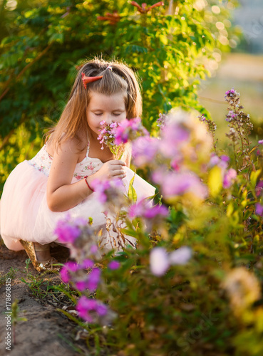 little girl beautiful smiling dancing in pink dress tutu as ballerina on sunny day happy childhood against a background of blooming summer in flowers