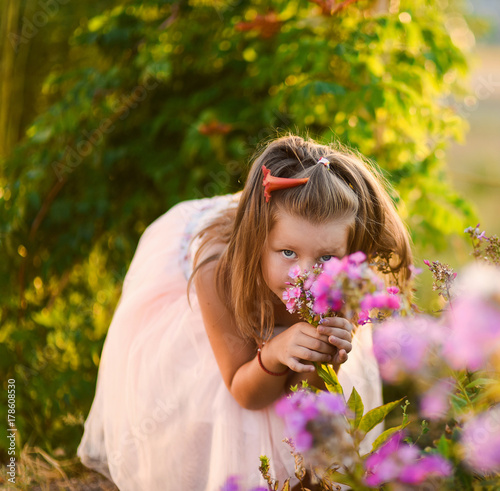little girl beautiful smiling dancing in pink dress tutu as ballerina on sunny day happy childhood against a background of blooming summer in flowers