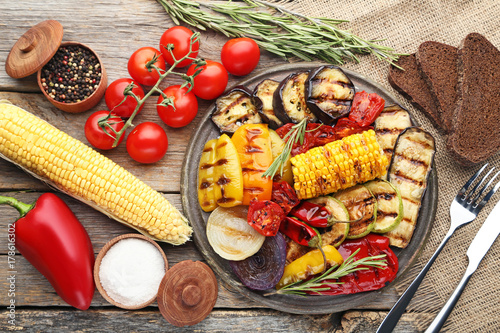 Grilled vegetable on brown cutting board with salt, pepper and bread