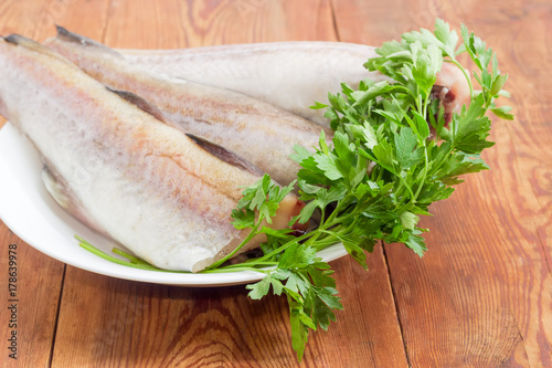 Uncooked carcasses of the Alaska pollock with parsley closeup