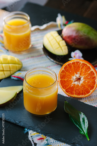 Fresh mango and orange detox drink over black slate.
