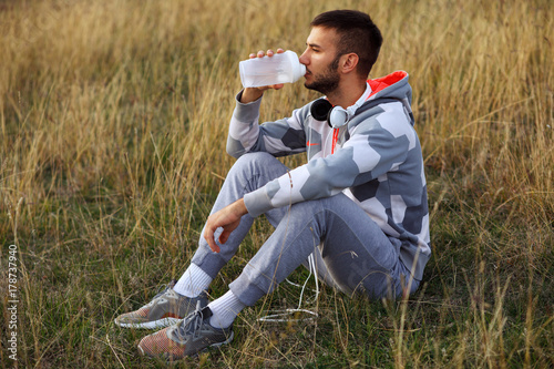Young man drinking water after jogging