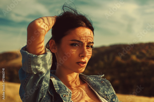 Portrait of a young woman with shadows texture on the face in a meadow with