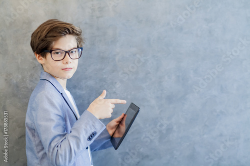 Teen schooler boy in eyeglasses holds tablet PC