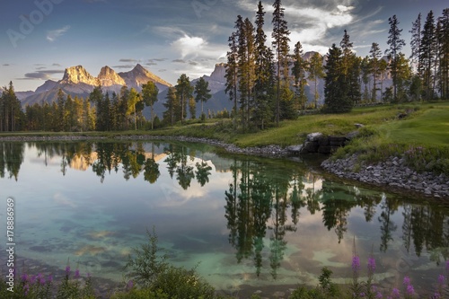 Plakat Refleksje nad jeziorem w słynnym polu golfowym Silvertip nad miastem Canmore z odległym krajobrazem Widok z góry trzy siostry w Alberta Pogórze w pobliżu Parku Narodowego Banff