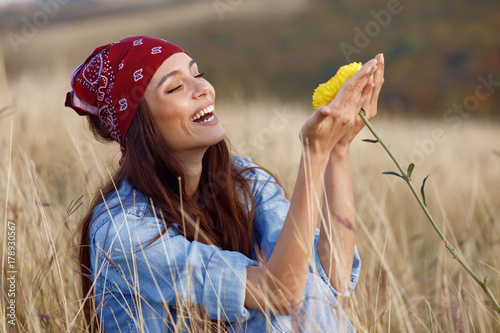 Beautiful young woman smells a flower in a meadow