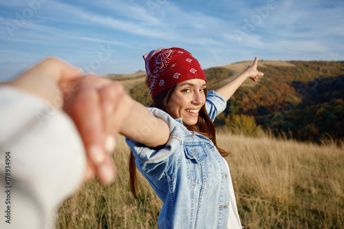 Happy young woman holds the hand of a man in nature