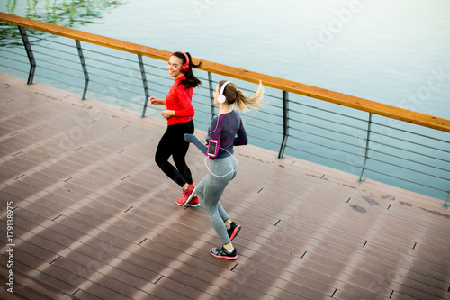 Two young women running by river