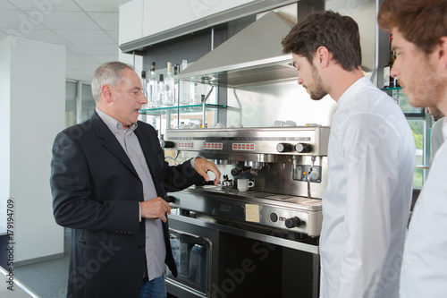 manager shows his employees how to use coffee machine