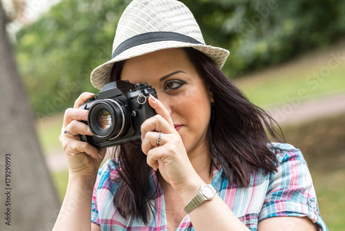 Beautiful young woman taking pictures in a park