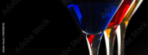 Colorful Cocktails in Martini Glasses on Black Background. Bar Commercials Concept.