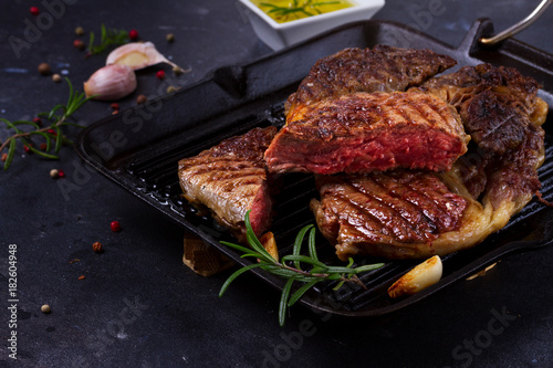 Obraz na płótnie Grilled juisy beef steak in pan with spices on dark stone background