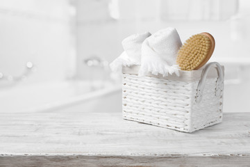 Basket, towels and bath brush on wood over blurred bathroom