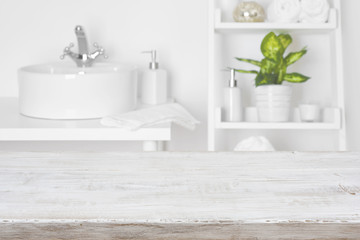 Wooden table in front of blurred white bathroom shelves background