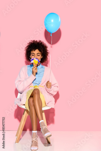 Фото: african american woman with flowers in ice cream cone and balloon in hands on pink wall backdrop african american woman with flowers in ice cream cone and balloon in hands on pink wall backdrop