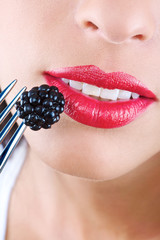 Mouth of a young woman and an appetizing blackberry. Icon of healthy eating.