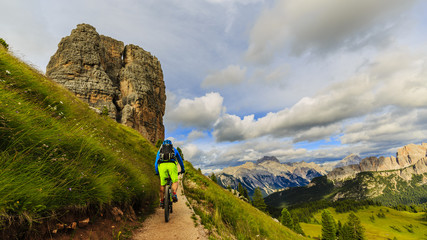 View of cyclist riding mountain bike on single trail in Dolomites, Cinque Torri, South Tirol, Italy