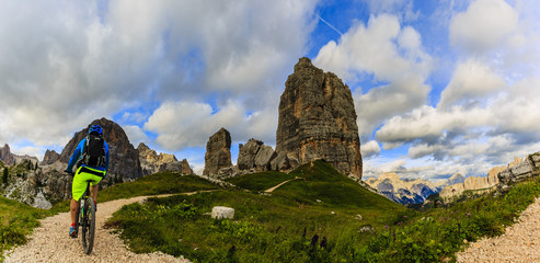 View of cyclist riding mountain bike on single trail in Dolomites, Cinque Torri, South Tirol, Italy