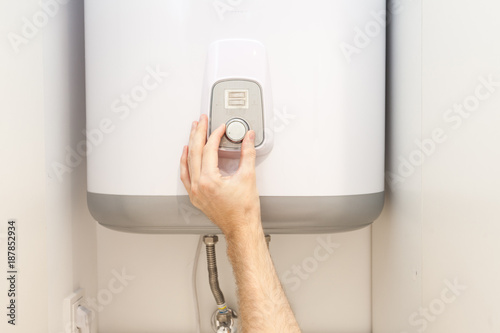 Fotoobraz na płótnie Zakończenie mężczyzna wręcza ustawiać temperaturę woda w Elektrycznym bojlerze