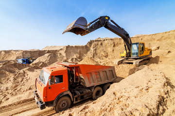 Excavator Loading Dumper Truck at sunny day