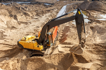 Excavator Loading Dumper Truck at sunny day