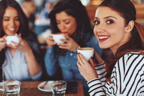 Three young women enjoy coffee at a coffee shop
