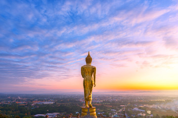 Golden buddha statue in Thai temple with cityscape view in the morning, Wat Phra That Khao Noi on a mountain at Nan, Thailand.