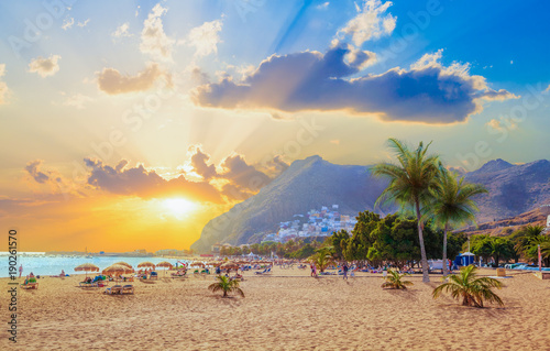Plakat Piękna lato scena na Teresitas plaży z ludźmi cieszy się wakacje w zmierzchu świetle w Tenerife, wyspa kanaryjska Hiszpania