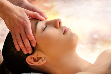 Massage therapist touching sensitive area between eyes on woman.