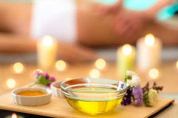 Still life of aromatic Ayurvedic massage oils with therapist in background.