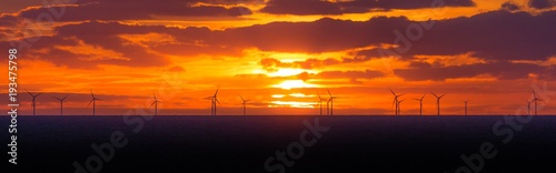 Zdjęcie XXL Panoramiczny zachód słońca z turbin wiatrowych w morskiej farmy wiatrowej. Wiele turbin wiatrowych w morzu i chmury na niebie. Energia elektryczna, która jest zrównoważona, alternatywna, odnawialna, ekologiczna i zapobiega zmianom klimatycznym