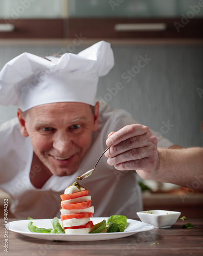 Fotoobraz na płótnie Szef kuchni przygotowuje przekąskę z mozzarellą i sosem pesto.